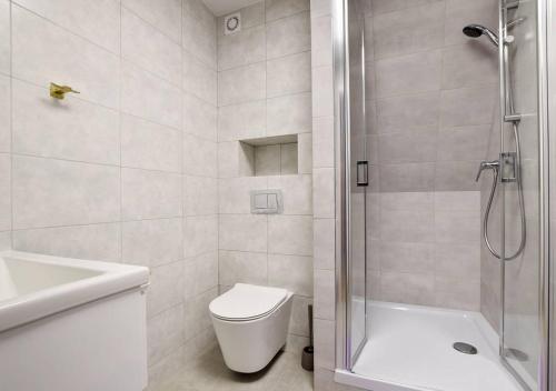 a bathroom with a shower and a toilet and a sink at Słoneczna Willa & sauny in Kudowa-Zdrój