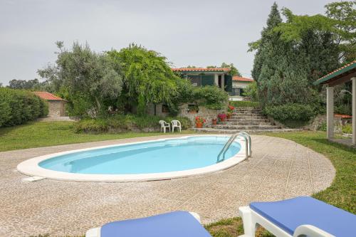 a swimming pool with two chairs and a house at Charming granite cottage in beautiful surroundings in Casal Diz