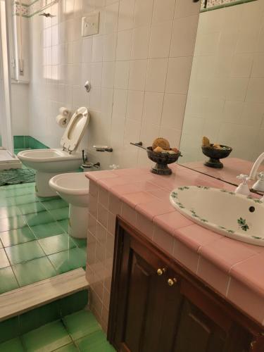 a bathroom with a sink and a toilet and a mirror at Casa MAIO, attico molto panoramico, in centro storico in Taormina