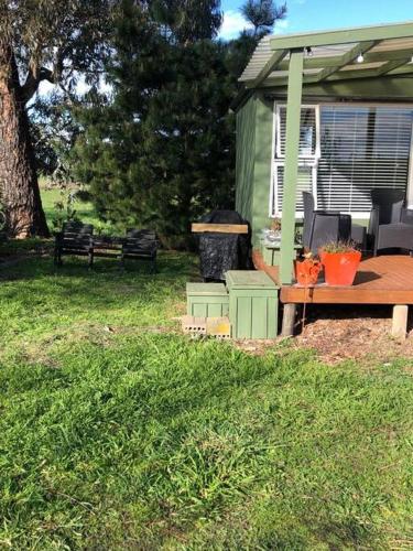 a green house with a picnic table and a bench at Fantail at Bluestone Retreat in Leeston