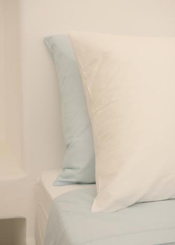 a white bed with white sheets and pillows at Amorgos Elegant Houses, 6 Villas in Amorgos