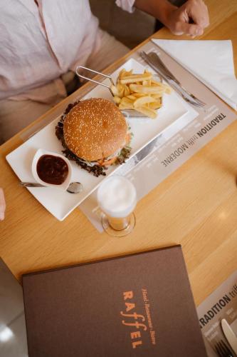 a hamburger and french fries on a table at Hotel Raffel in Jennersdorf