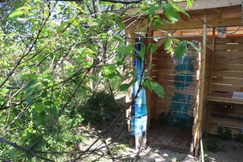 a wooden out house with a blue curtain in a tree at Halbinsel Resort Peenemünde in Peenemünde