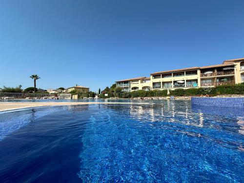 une piscine d'eau devant un hôtel dans l'établissement Appartement climatisé avec piscine et jardin à l'entrée du Golfe de St Tropez, à La Garonnette-Plage
