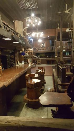 a restaurant with a bar with wooden tables and chairs at Ruean Mai Chai Khlong in Amphawa