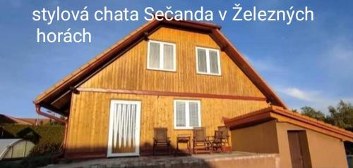 a large wooden house with chairs in front of it at Apartmánová chata Sečanda s bazénem, u Sečské přehrady in Seč