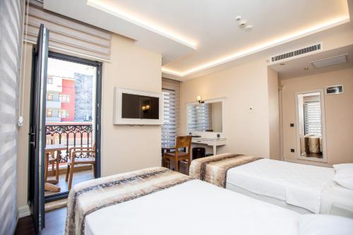 two beds in a hotel room with a balcony at Opatija Hotel in Istanbul