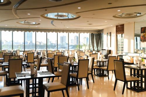 a dining room with tables and chairs and windows at Brilliant Hotel - Afternoon Tea Inclusive in Da Nang