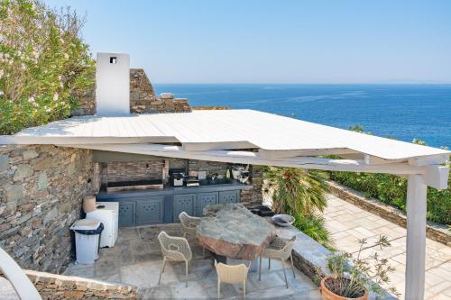 a patio with a table and a kitchen under a roof at Blueros Luxury Villa in Megas Yialos-Nites