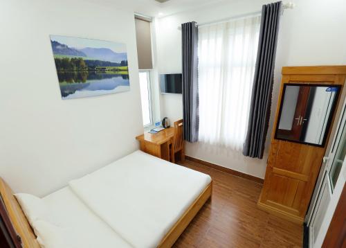a bedroom with a white bed and a window at Maxim Hotel in Da Lat