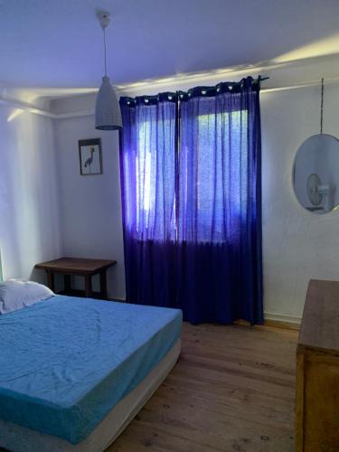 Un dormitorio con una cama y una cortina azul. en Au coeur des arbres, en Dieulefit