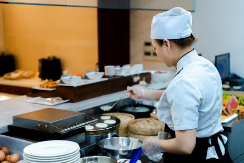 a woman in a kitchen preparing food at Brilliant Hotel - Afternoon Tea Inclusive in Da Nang