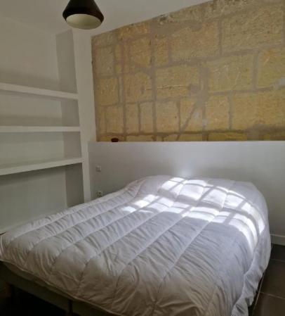 un lit dans une chambre avec un mur de briques dans l'établissement Appartement au rez-de-chaussée, à Arles