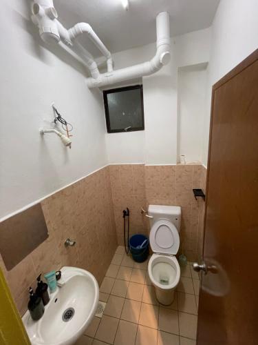 a bathroom with a toilet and a sink at Peaceful Pines 4 ROOMS FULL AC & NETFLIX by EZYROOM MELAKA in Ayer Keroh