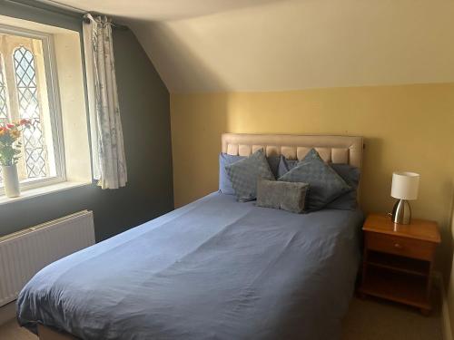 a bedroom with a bed with blue sheets and a window at Trowbridge Lodge in Trowbridge