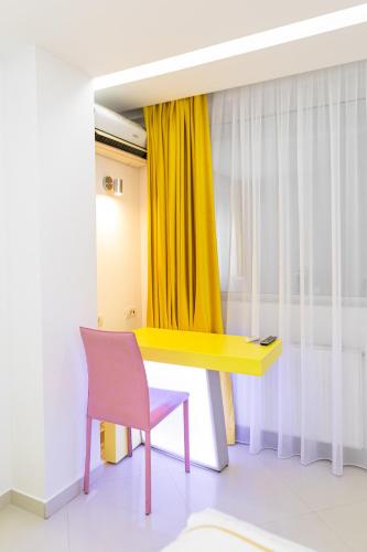 a room with a yellow desk and a pink chair at Christina Hotel in Bucharest