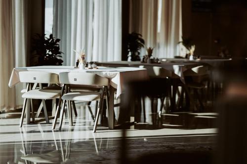 a dining room with tables and white chairs at Naos Luxury Hotel in Vlorë