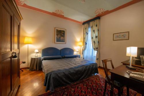 a bedroom with a blue bed and a desk at Palazzo Finati in Alba