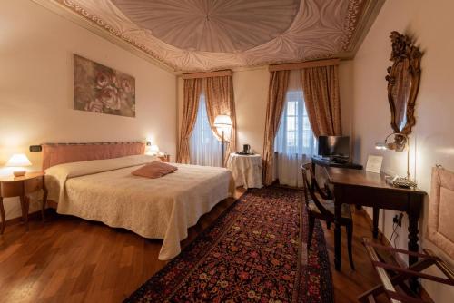 a bedroom with a bed and a table and a desk at Palazzo Finati in Alba