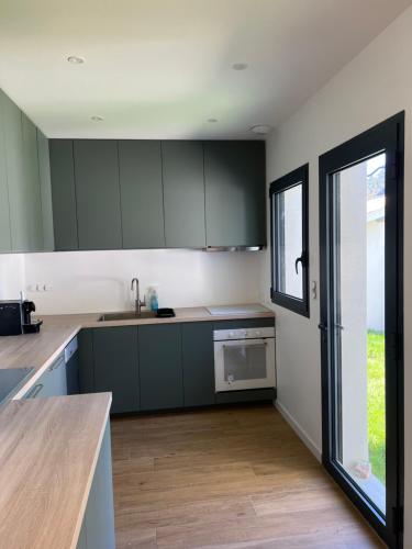 a kitchen with green cabinets and a large window at Relax plage et bassin in Le Porge