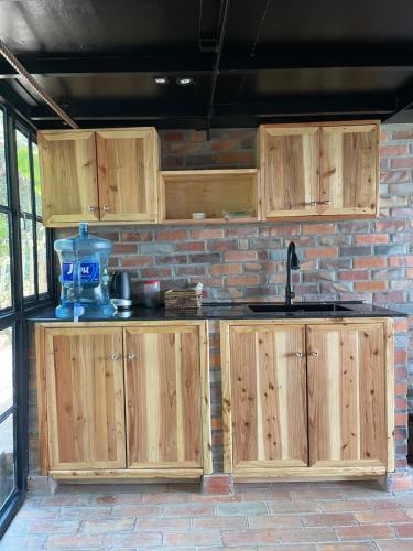 a kitchen with wooden cabinets and a brick wall at Eagle View Lodge - Kigali in Kigali