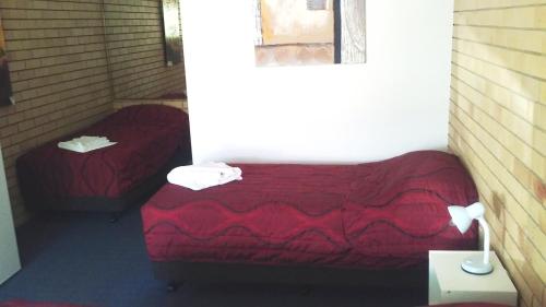 Habitación pequeña con 2 camas y ventana en Nambour Central Motel, en Nambour
