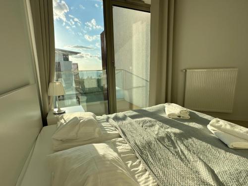 a bed in a bedroom with a large window at Pinea Apartments in Pobierowo