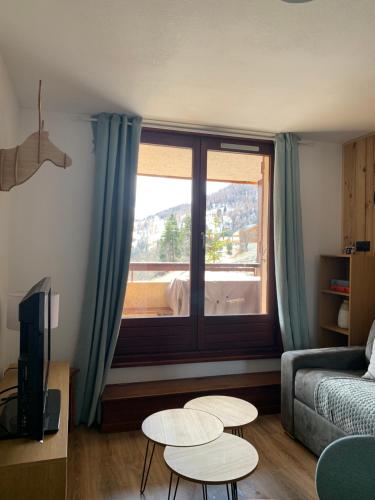 - un salon avec un lit, deux tables et une fenêtre dans l'établissement Cocon chaleureux, avec vue et au calme, à Uvernet