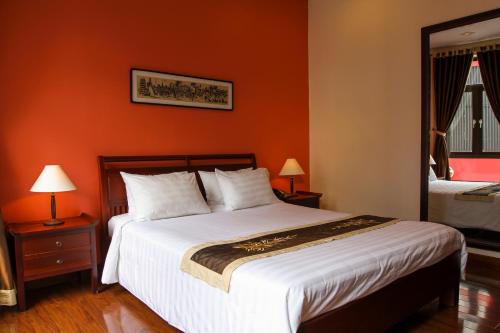 a bedroom with a large bed with an orange wall at Nam Bo Boutique Hotel in Can Tho