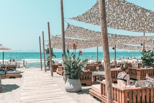 a woman sitting on a bench on the beach at Yacht Hotel in Vlorë