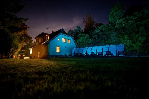 a blue house with chairs in a field at night at Villa with a covered pool, park, and playground in Svoboda nad Úpou