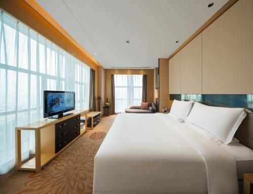 a hotel room with a large bed and a television at Grand Skylight International Hotel Ganzhou Chang Zhen Avenue in Ganzhou