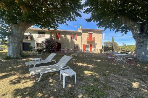 un groupe de chaises assises dans l'herbe devant une maison dans l'établissement La Maison de Constance - Charmante Maison provençale 3 chambres, à Aigues-Mortes