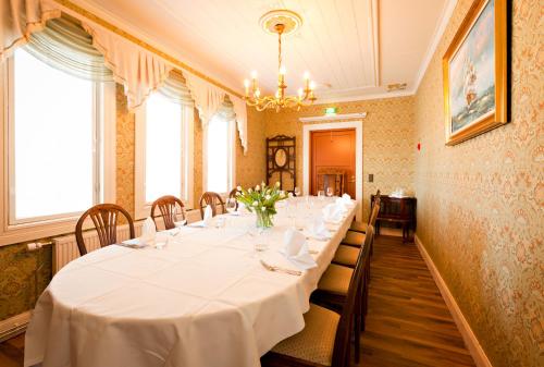 a dining room with a long table with white table cloth at Hotelli-Ravintola Alma in Seinäjoki