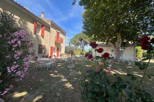een tuin met bloemen en een gebouw met een boom bij Gîte de la Cave - Charmant Gîte provençal avec une chambre in Aigues-Mortes