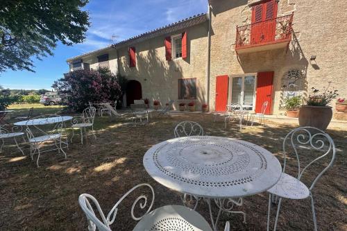 een groep tafels en stoelen voor een gebouw bij Gîte de la Cave - Charmant Gîte provençal avec une chambre in Aigues-Mortes