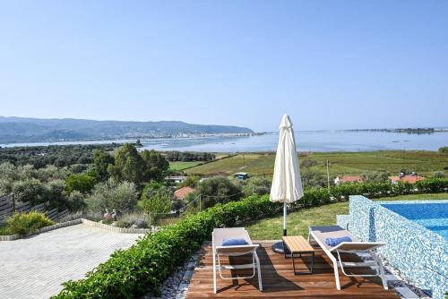 a patio with an umbrella and chairs and a swimming pool at Villa Flamingo Lefkada in Ayía Varvára