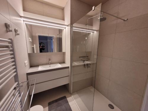 a bathroom with a sink and a shower with a mirror at residentie NAUSICAA in Blankenberge