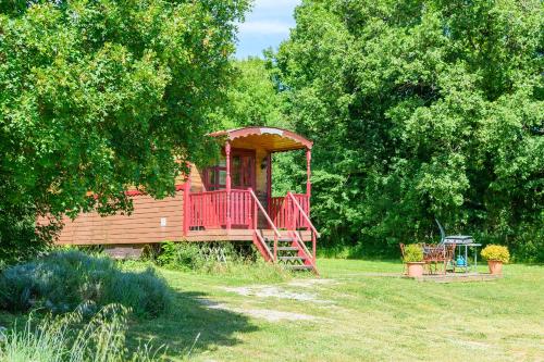 a wooden cabin with a red deck in a yard at Roulotte-Quinta La Grange d Emile in Blandas