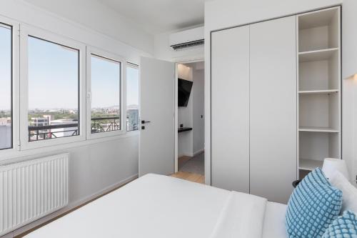 a bedroom with white walls and windows at Celine by halu!, Spacious apartments next to business hub in Thessaloniki