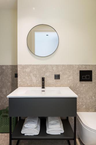 a bathroom with a sink and a mirror at Celine by halu!, Spacious apartments next to business hub in Thessaloniki