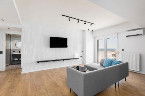 a living room with a couch and a tv on a wall at Celine by halu!, Spacious apartments next to business hub in Thessaloniki