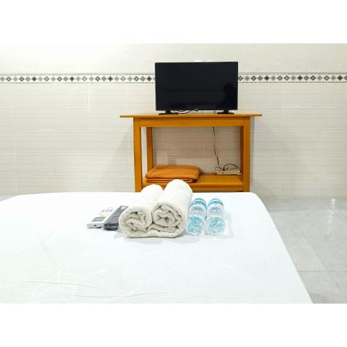 a bed with towels and a television in a room at Wisma Mekar Jaya near Solo Safari Mitra RedDoorz in Karanganyar