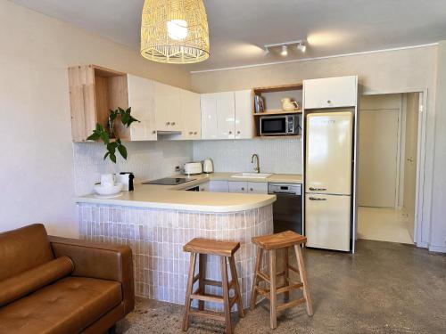 a kitchen with a refrigerator and two bar stools at Tropic Court Beach Escape in Coffs Harbour