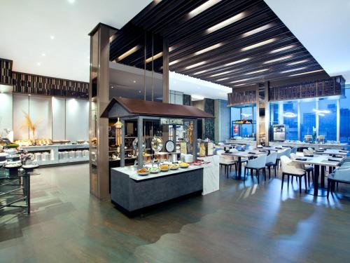 a restaurant with tables and chairs and a buffet at Platinum Hotel Tunjungan Surabaya in Surabaya