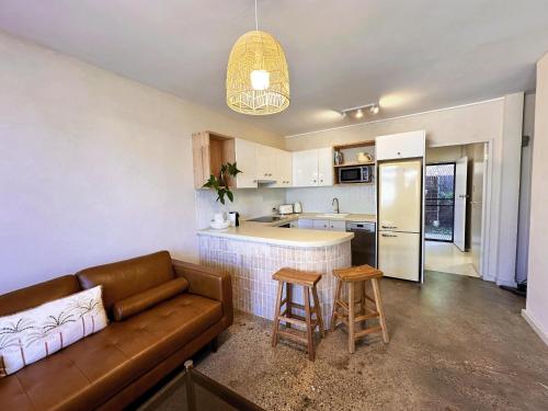 a living room with a couch and a kitchen at Tropic Court Beach Escape in Coffs Harbour