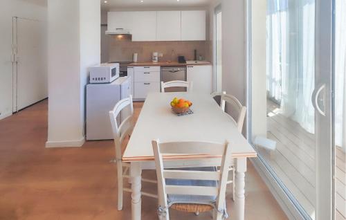 Il comprend une cuisine avec une table et des chaises blanches ainsi qu'une cuisine équipée d'un réfrigérateur. dans l'établissement Nice Apartment In Palavas-Les-Flots, à Palavas-les-Flots