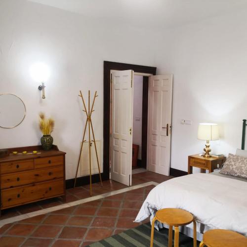 a bedroom with a bed and two chairs and a dresser at Los Alcornoquillos in Carratraca
