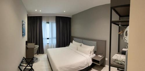 a bedroom with a white bed and a window at Suasana Suites Johor Bahru City Centre in Johor Bahru