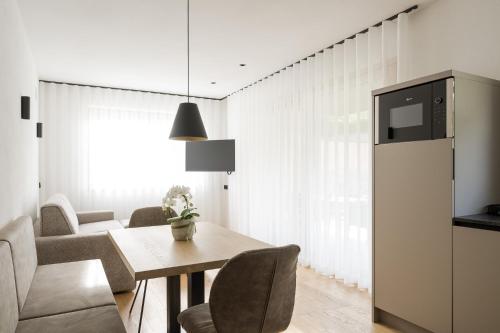 a kitchen and dining room with a table and chairs at Apartsuites Rosengarten in Lagundo